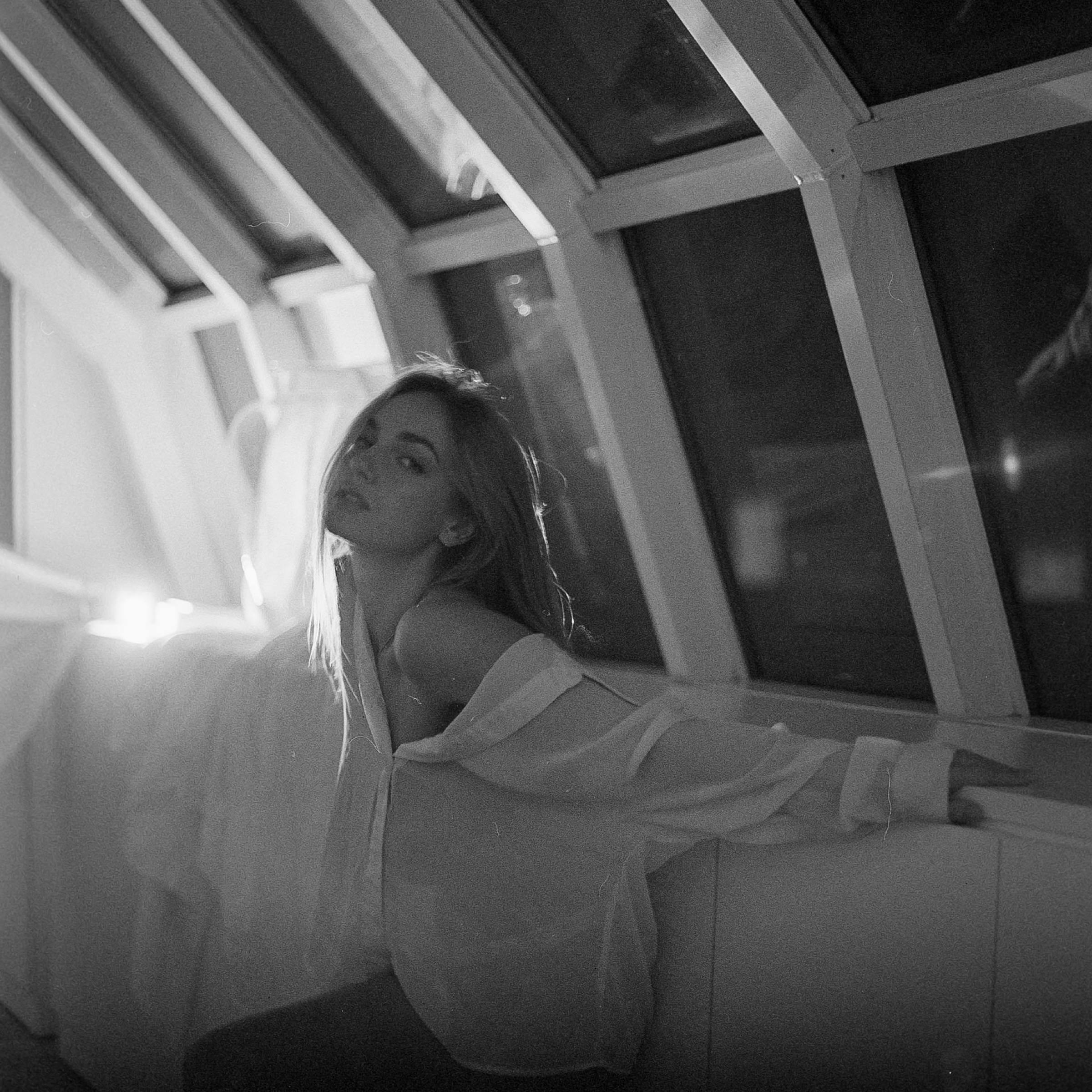 Anastasia reclining in color against a dark interior
