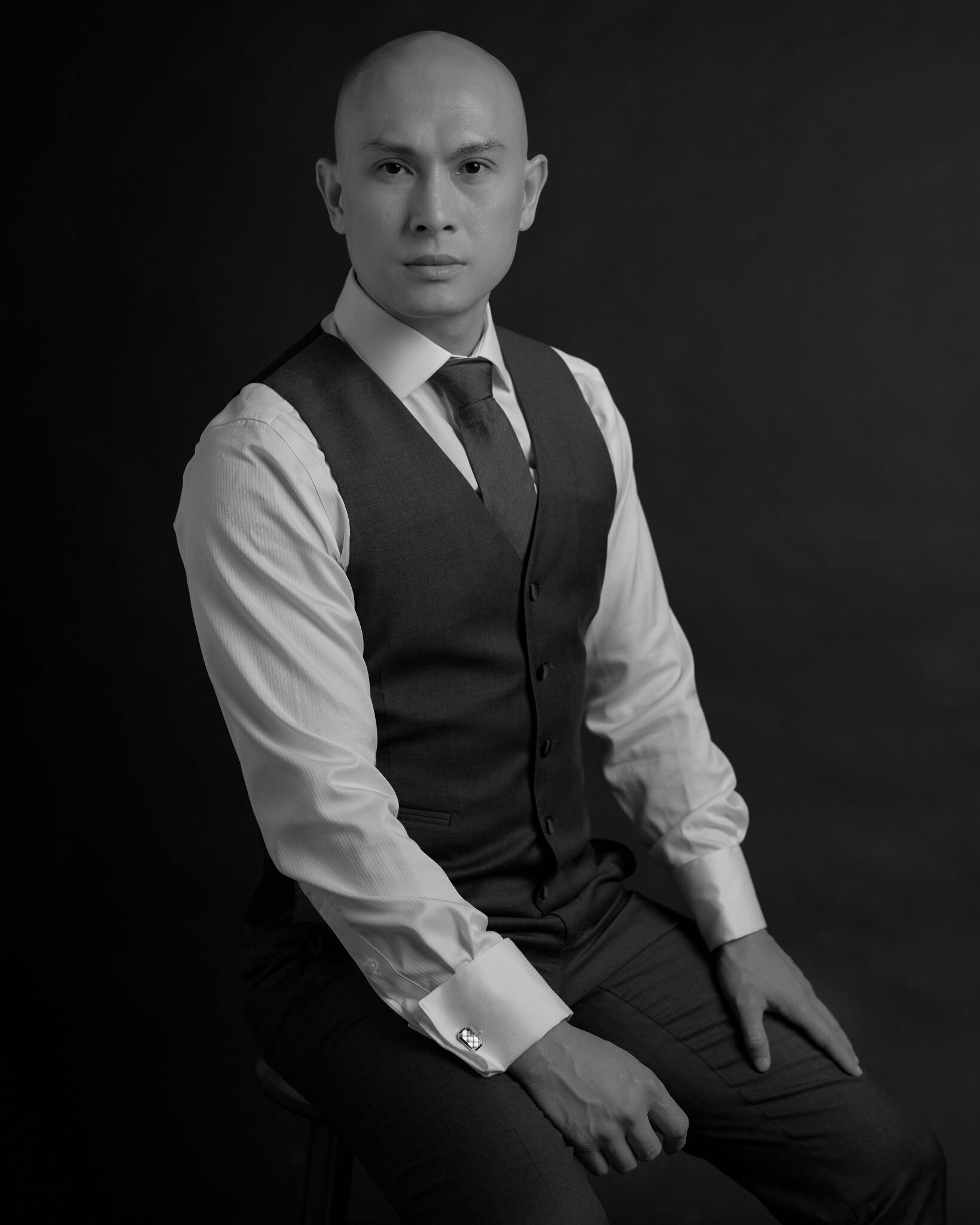 Black and white seated portrait of a man in a vest and tie