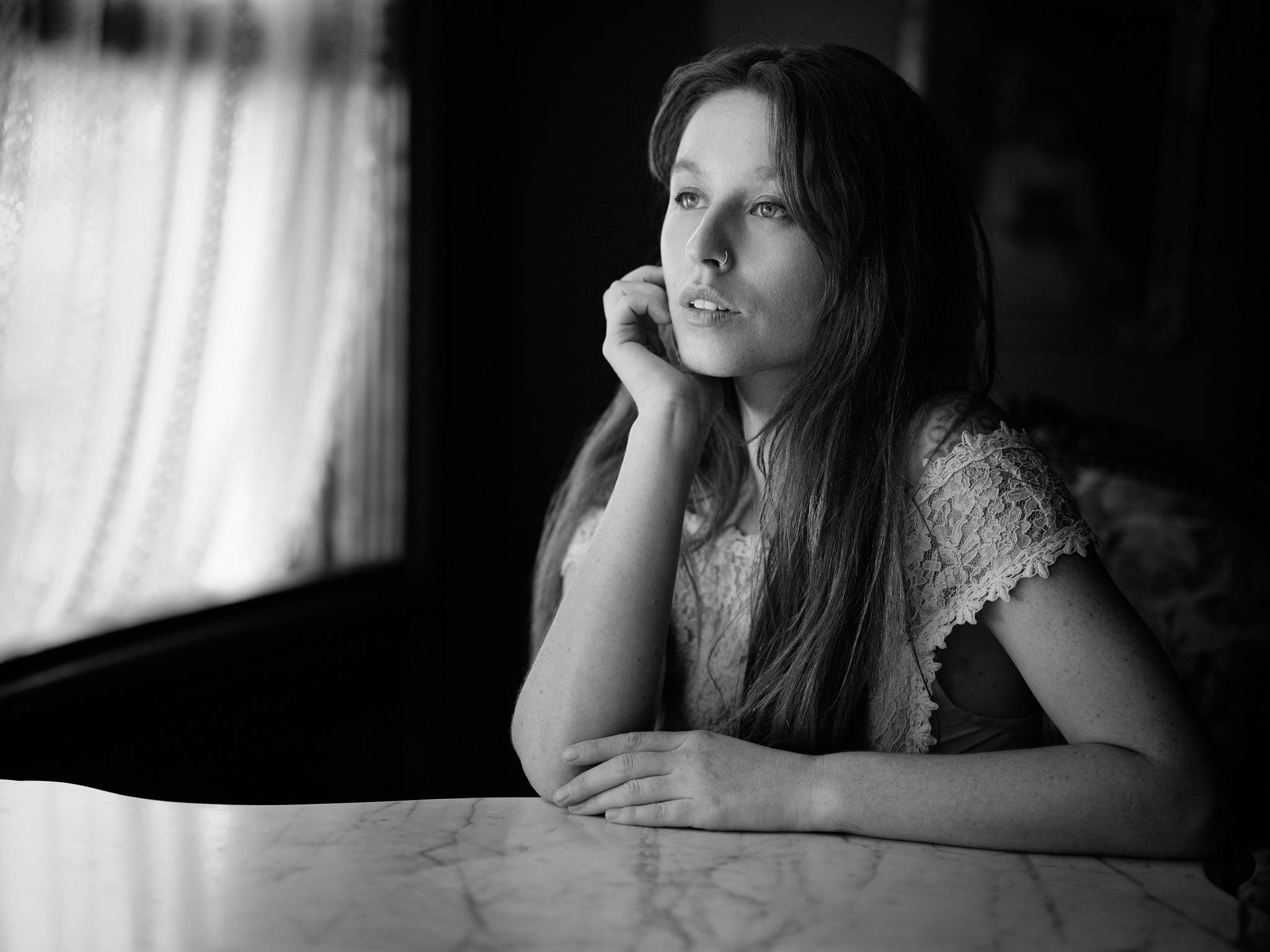Kisa at a marble table by a curtained window
