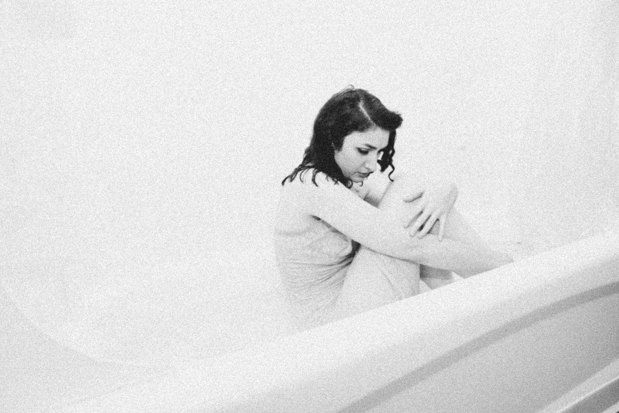 Megan sitting in a bathtub, arms around her knees