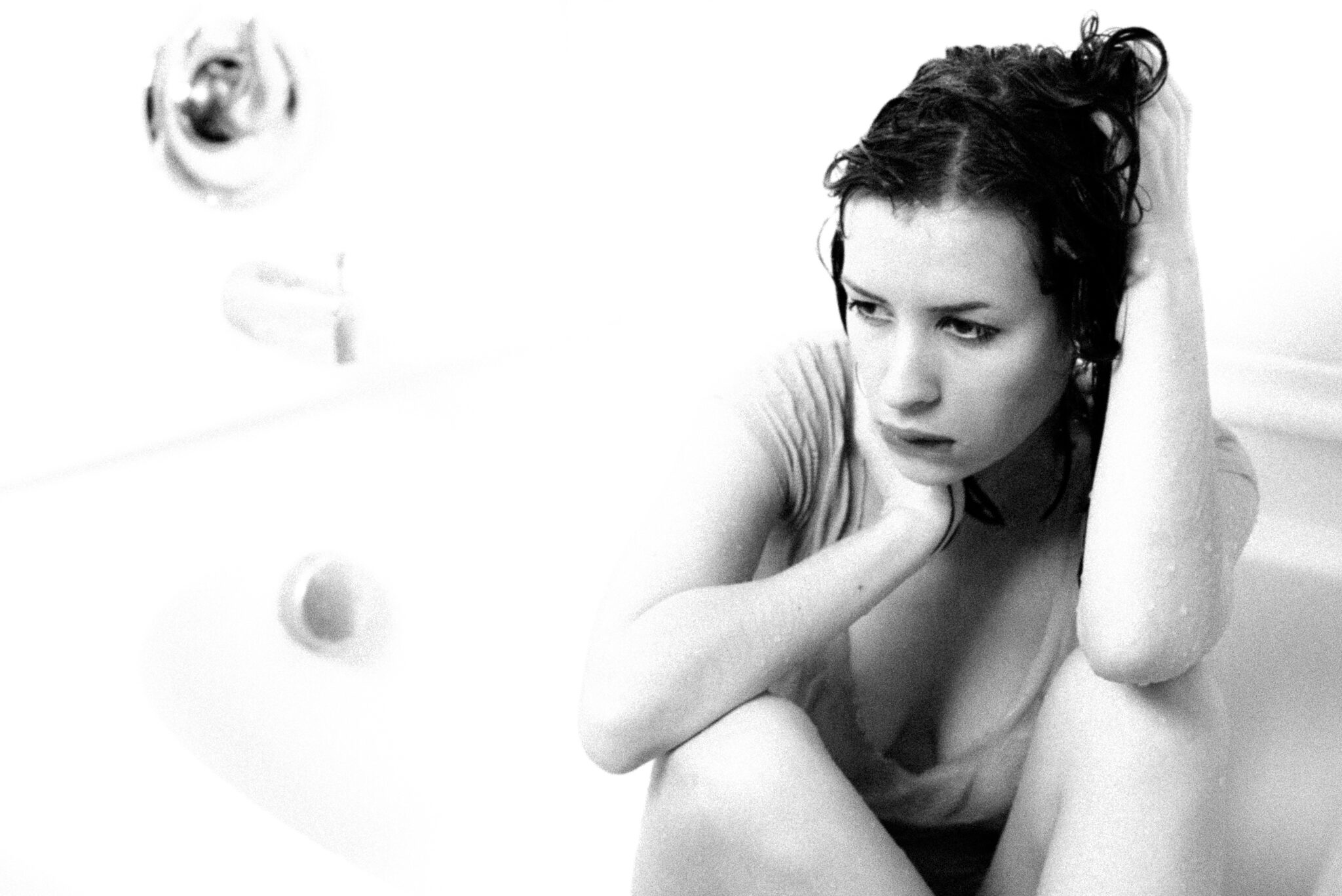 Uli sitting in a shower, looking away